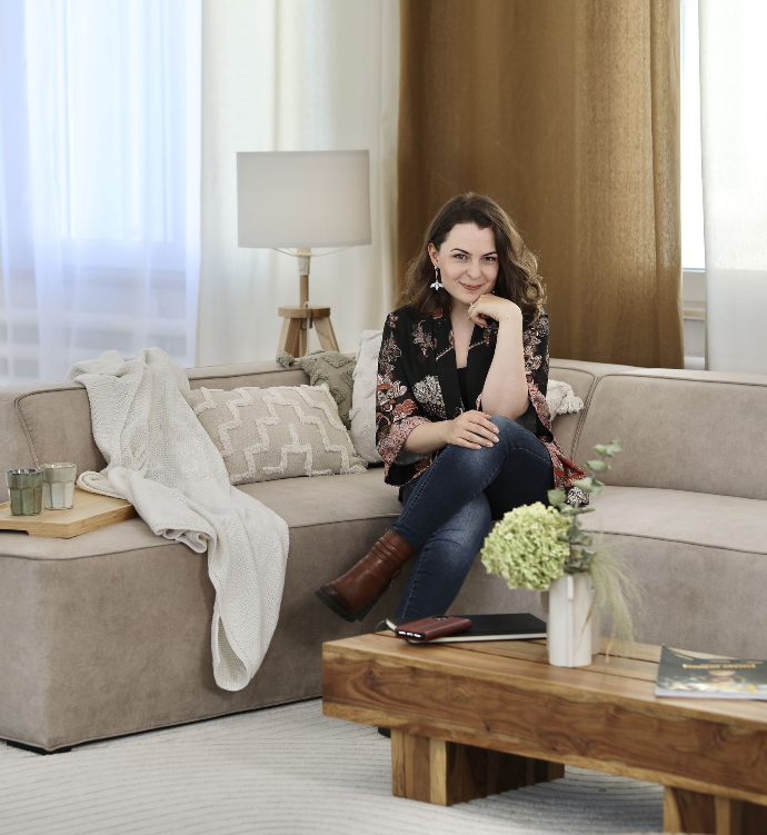 Judith Müller sitzt auf einer Couch und lächelt in die Kamera